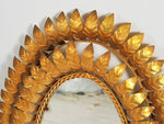 A 1950's French oval mirror with double layer of surrounding gold metal leaves