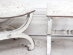 A pair of 19th C white painted scroll legged stools upholstered in cowhide