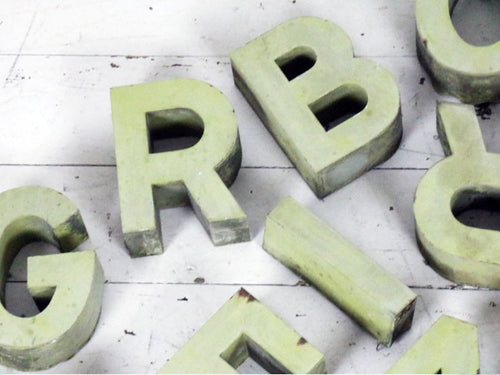 A set of 18 green painted metal shop letters